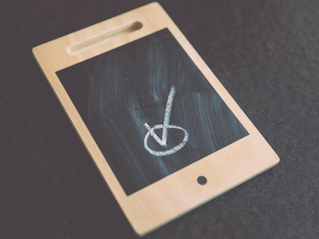 A small wooden chalkboard with a white checkmark drawn on it.
