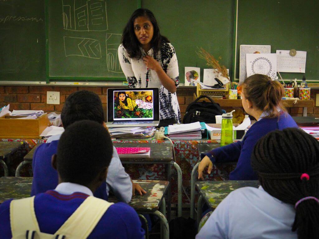 A teacher standing in front of a classroom, engaging with students.