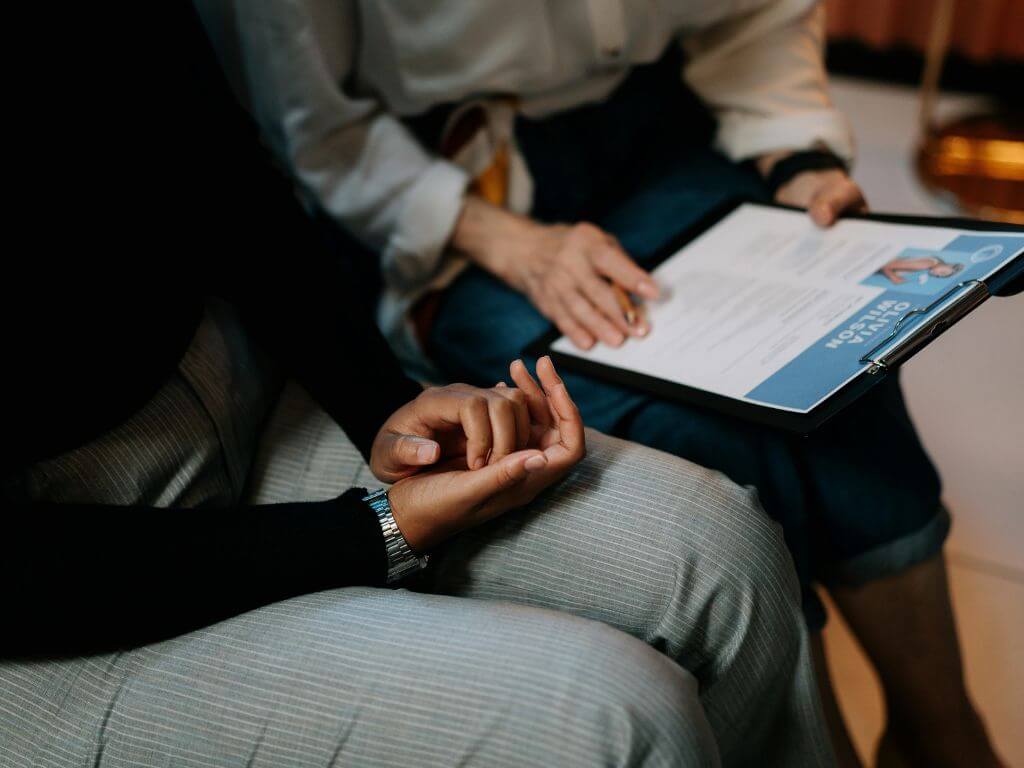 A close-up of two people in a job interview, one holding a resume.