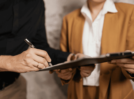 Close up of two professional people, signing a document. 