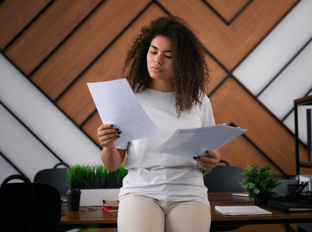 A recruiter sitting against a desk comparing two resumes.