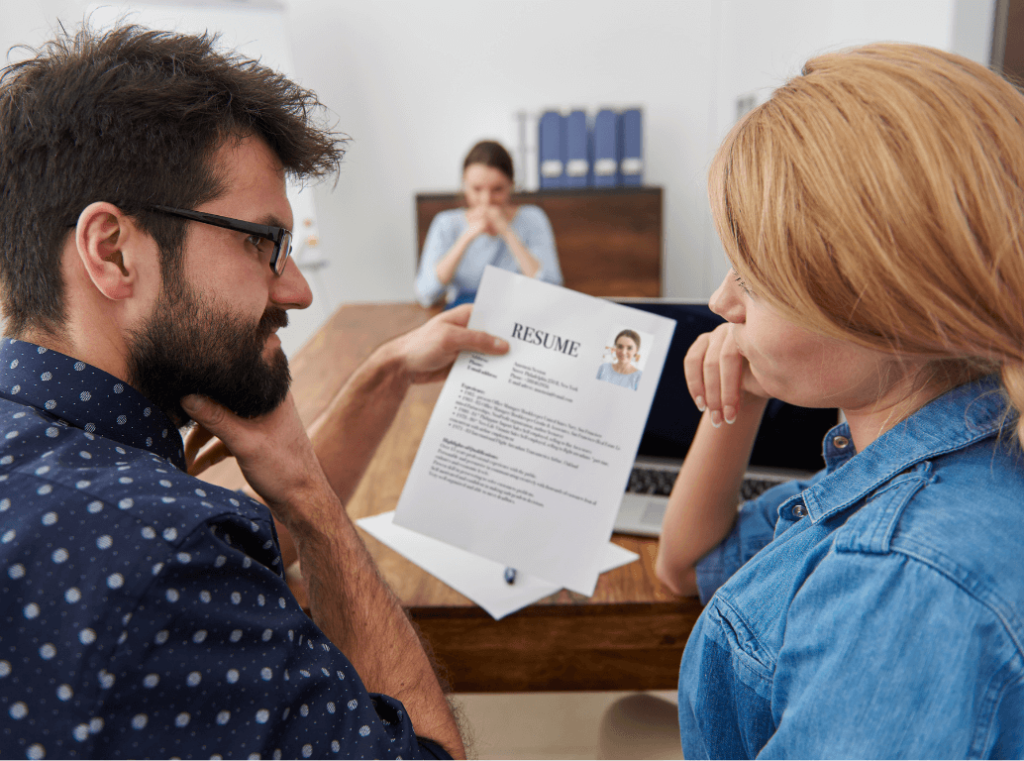 Two recruiters closely reviewing a printed CV together during a candidate assessment discussion.