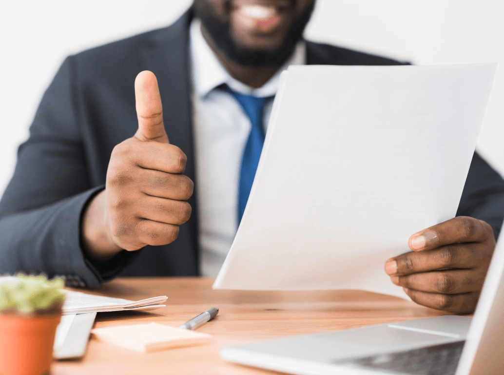 A successful job candidate holding their background screening documents and giving a thumbs up.