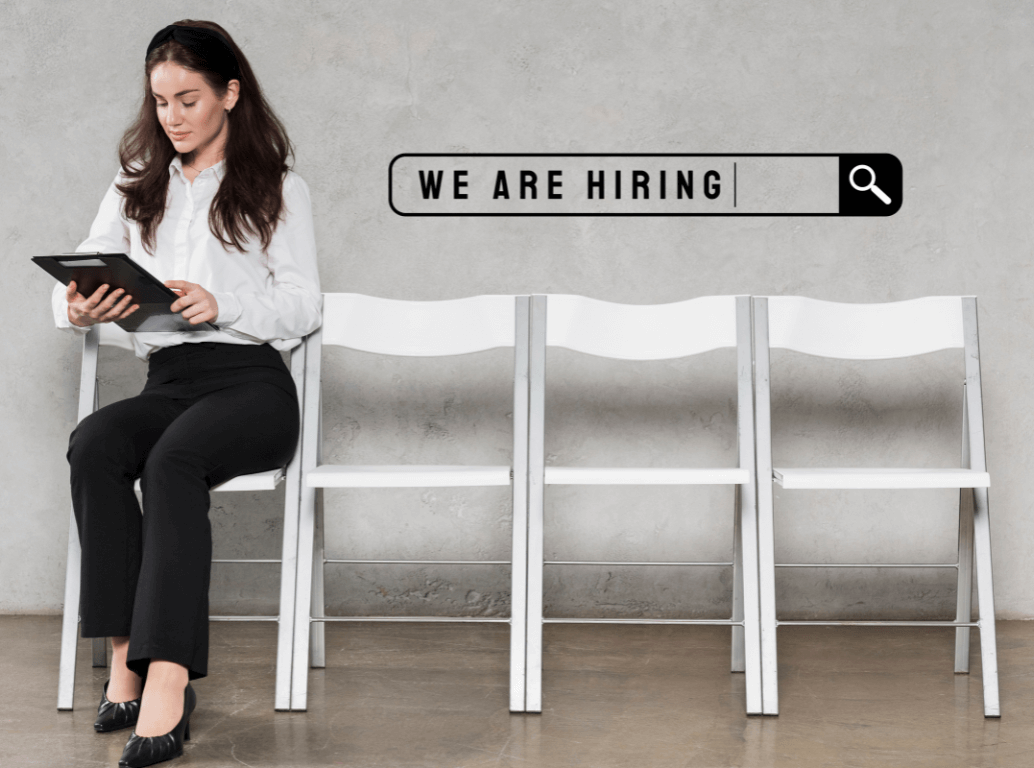 Woman sitting on a chair in a waiting area reading a tablet, with a “We are hiring” search bar graphic on the wall behind her.