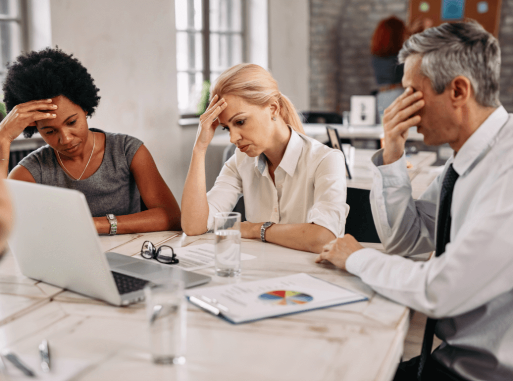 Stressed team with low morale looking frustrated during a meeting