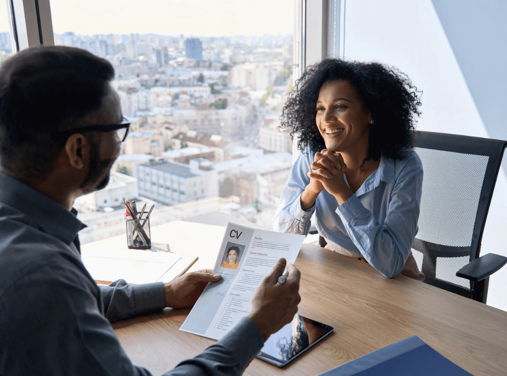 Hiring manager holding a candidate’s CV while interviewing them.