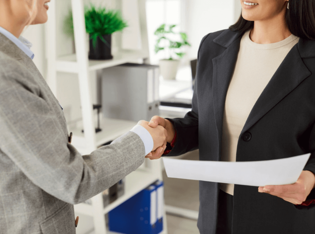 Two professionals shaking hands after a successful hiring discussion.