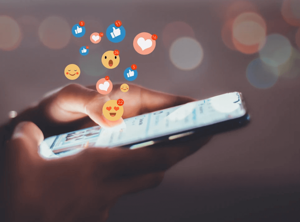 A person's hands holding a smartphone and tapping the screen with floating social media notification icons.
