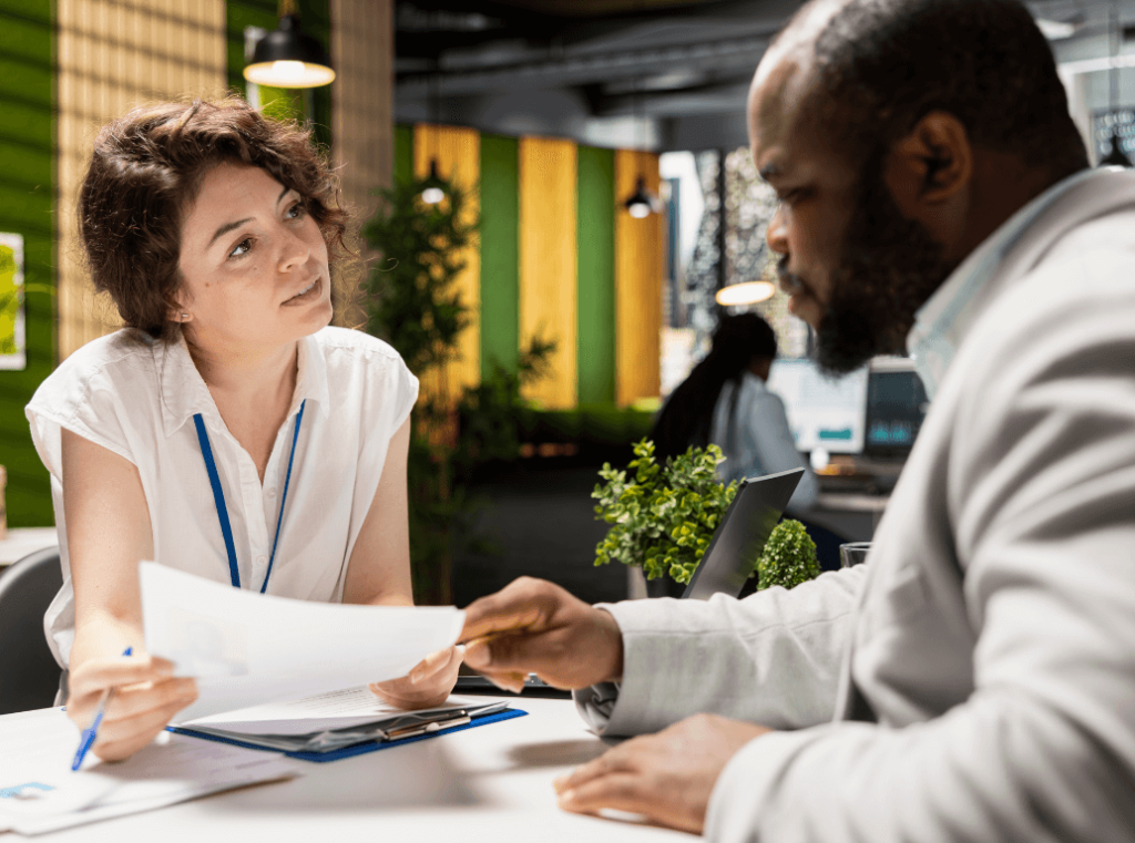 An interviewer listening and reviewing a candidate’s CV during an interview.