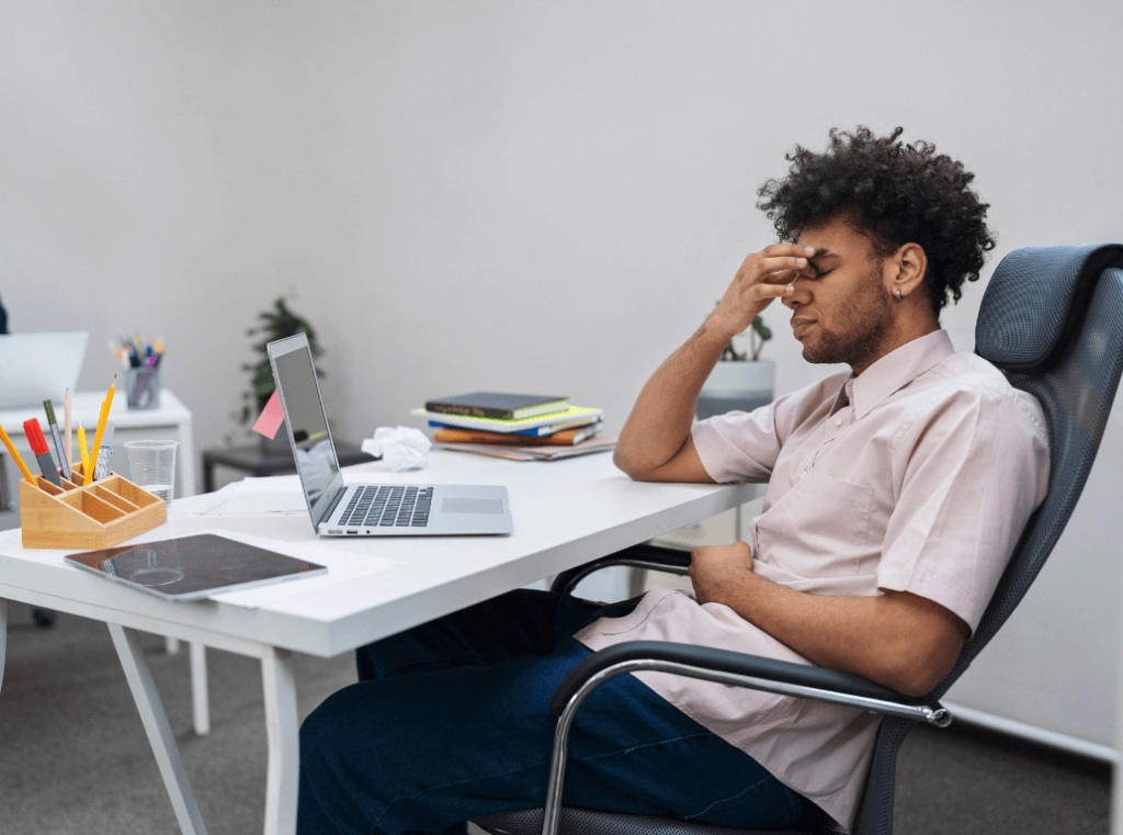 A stressed professional holding his head in his hands, illustrating the consequences of a bad hire or recruitment risk.