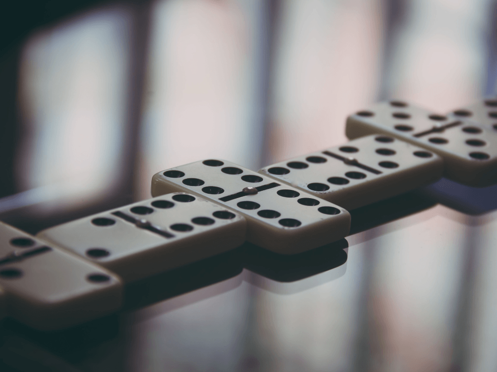 Connected domino pieces on a table, showing the cause-and-effect of connecting the dots in pre-employment checks.