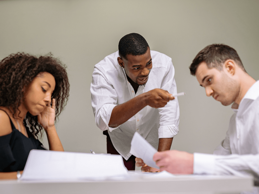 An aggressive employee causing conflict in an office meeting, showcasing the negative impact of a bad hire.