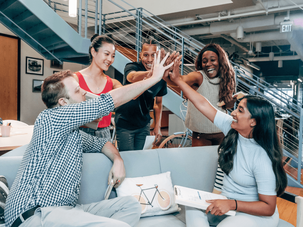 Happy young professionals celebrating a win with a high-five in a modern workspace.